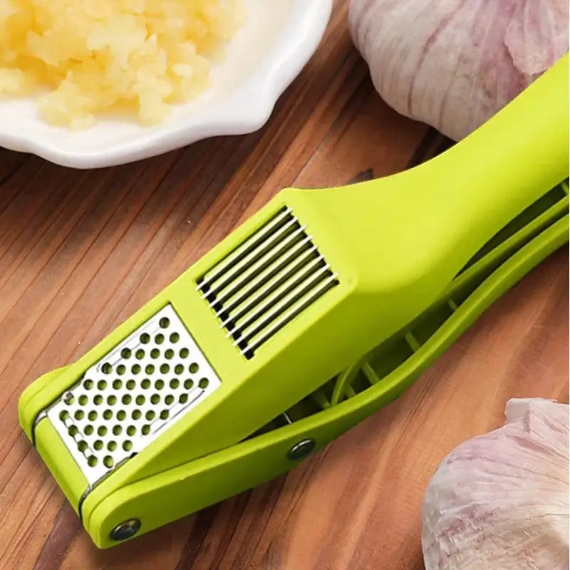 2-in-1 Garlic Press and Slicer, Green Options on a wooden surface with garlic cloves and minced garlic.