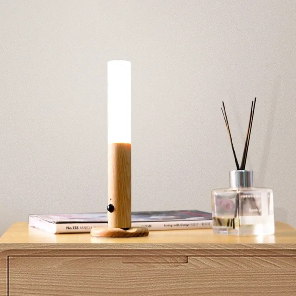 Rechargeable motion sensor night light with wood base on bedside table next to books and diffuser