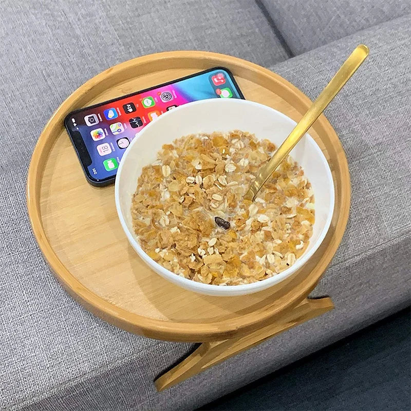 Sofa armrest tray holding a bowl of cereal and a phone.