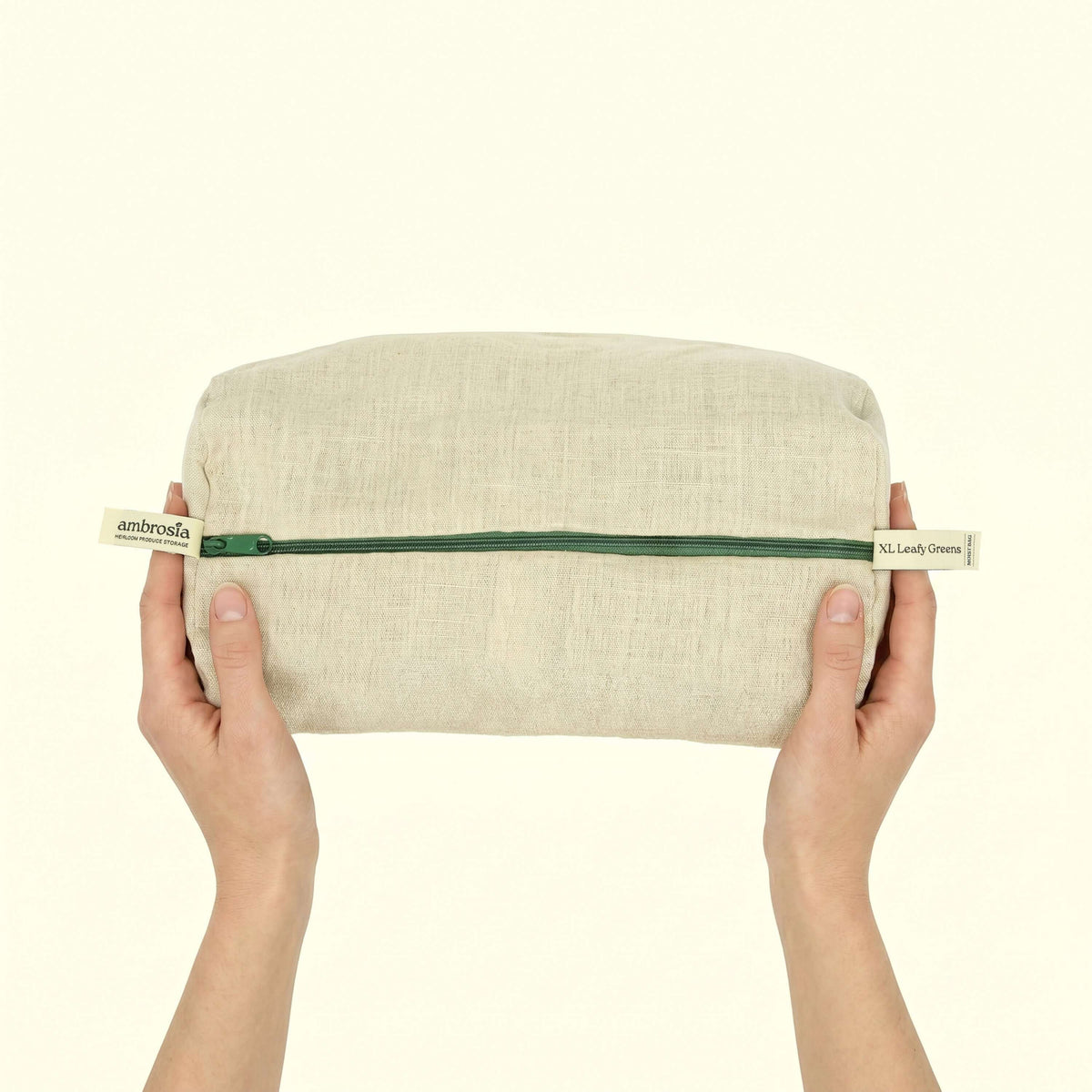 Ambrosia XL Leafy Greens Storage Bag held in hands, showcasing its breathable design for fresh greens.