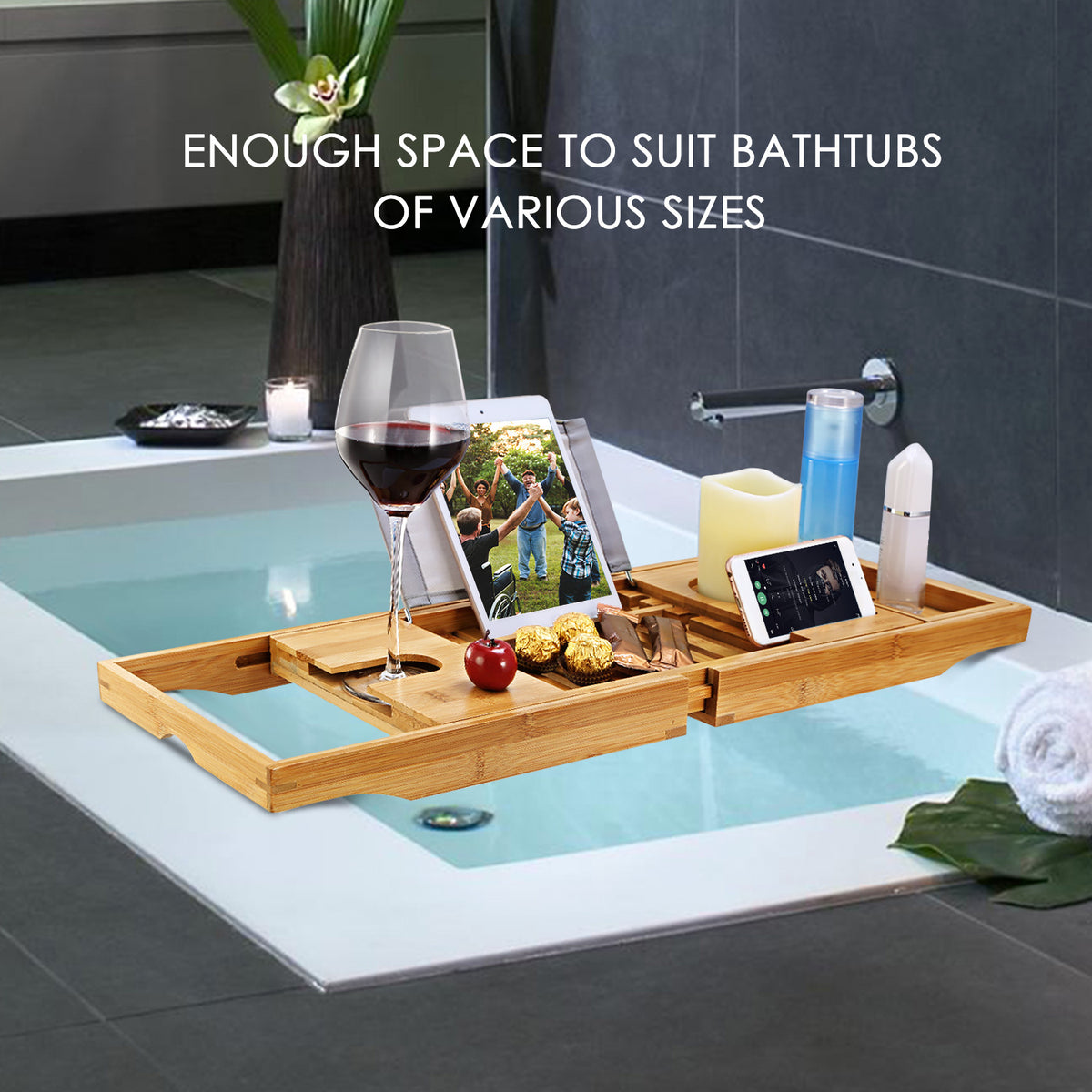 Extendable bamboo bathtub caddy with book holder displaying wine glass, book, and drink holders across bathtub