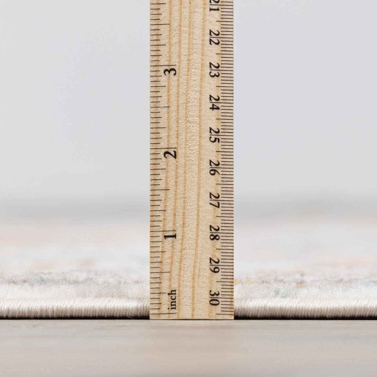 Elegant area rug thickness measurement with a ruler showing clear dimensions.