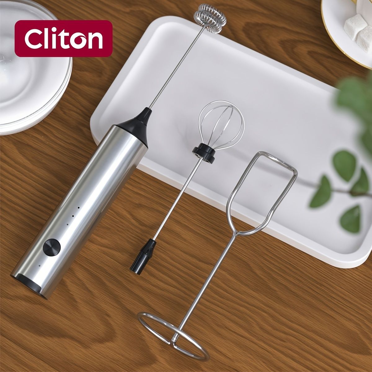 Rechargeable handheld milk frother in silver with black grip and 2 interchangeable whisk heads stored in white case