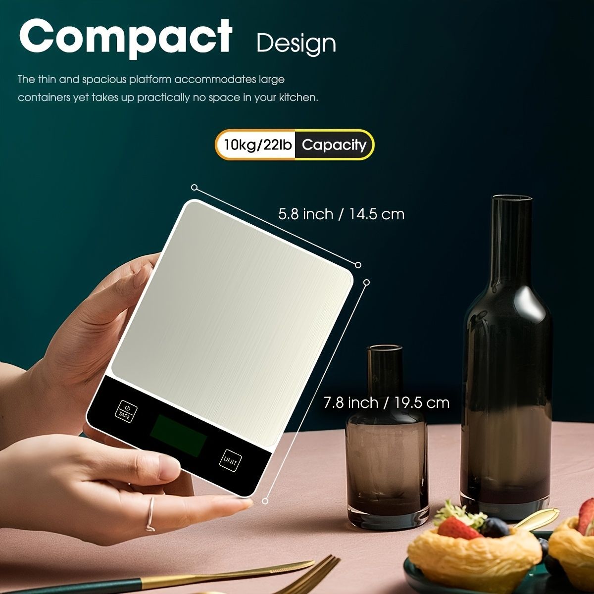 Compact stainless steel digital kitchen scale 22 lb with white platform held in hand, showing 22lb capacity next to wine bottles and pastries