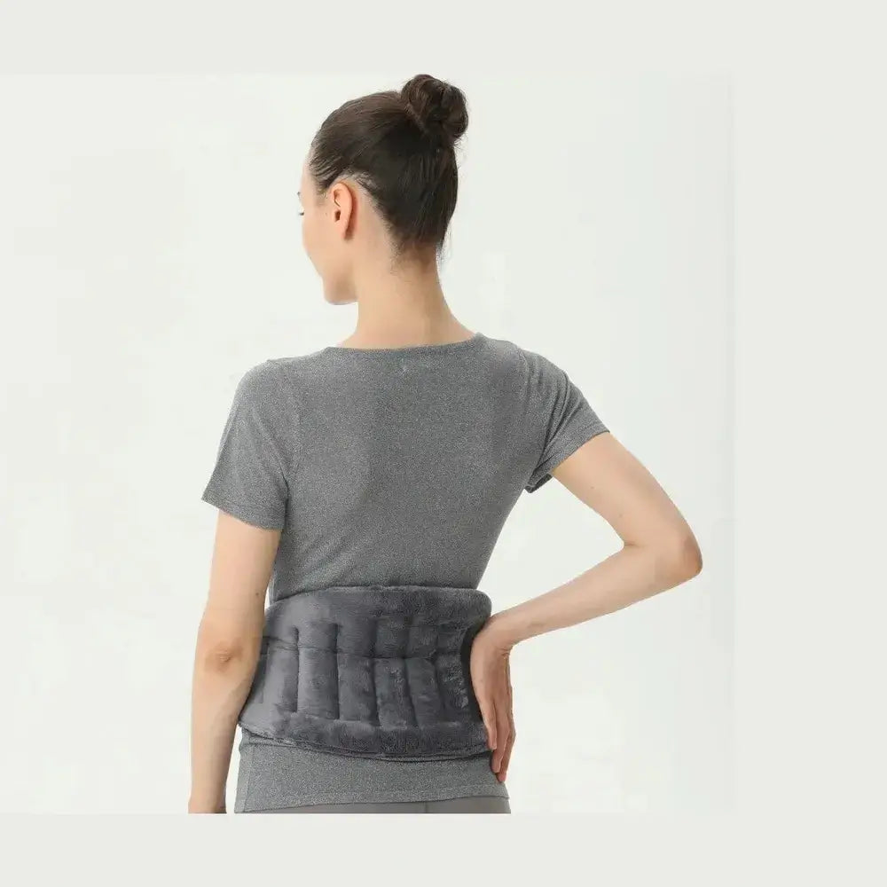 A woman using a microwave heating pad wrap on her back for soothing warmth and comfort, featuring a fleece exterior and adjustable strap.