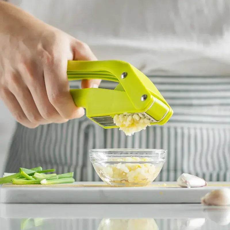 2-in-1 Garlic Press and Slicer, Green Options in use, showing garlic being pressed into a bowl.