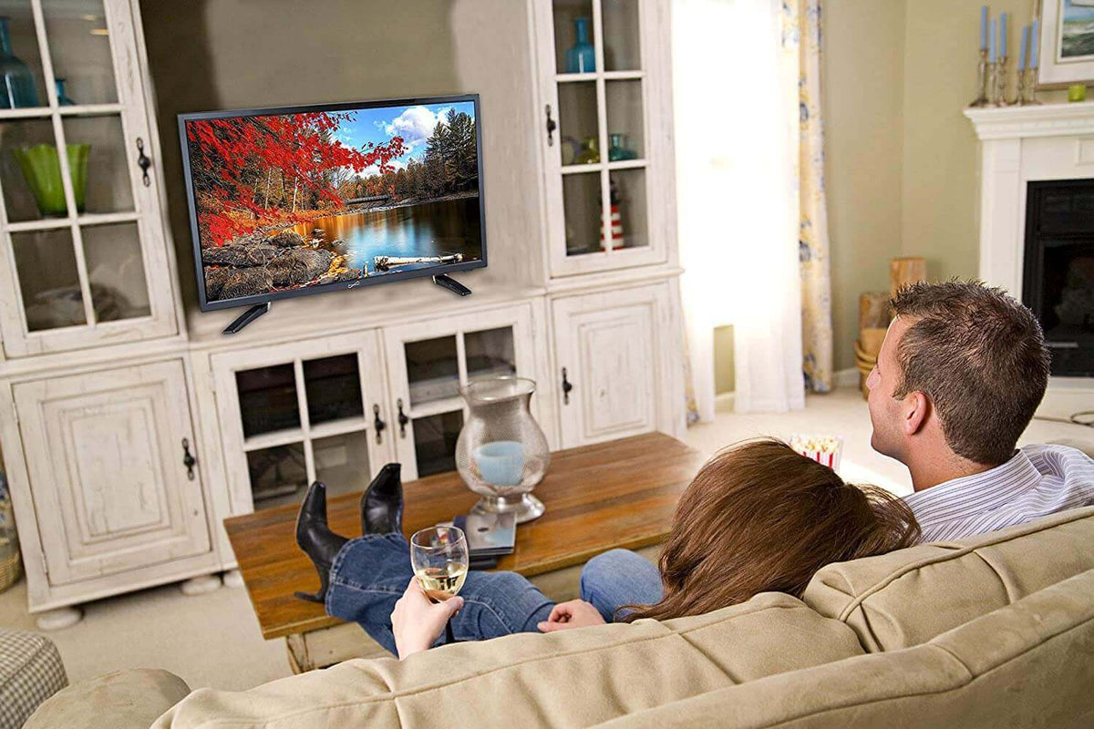 Couple enjoying a movie on a 24-inch AC DC LED TV for RV in a cozy living room setting.