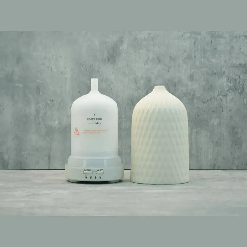 color-changing ceramic essential oil diffuser displayed beside a modern humidifier on a textured surface.