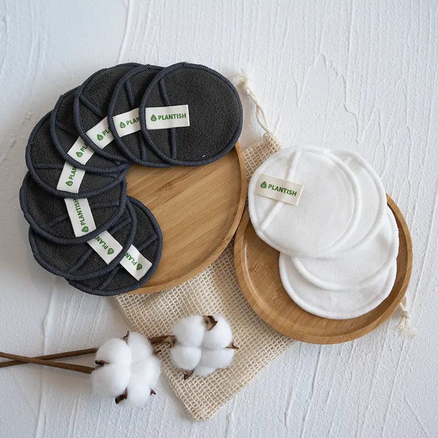 reusable bamboo charcoal cotton rounds in charcoal and white on wooden trays with cotton plant