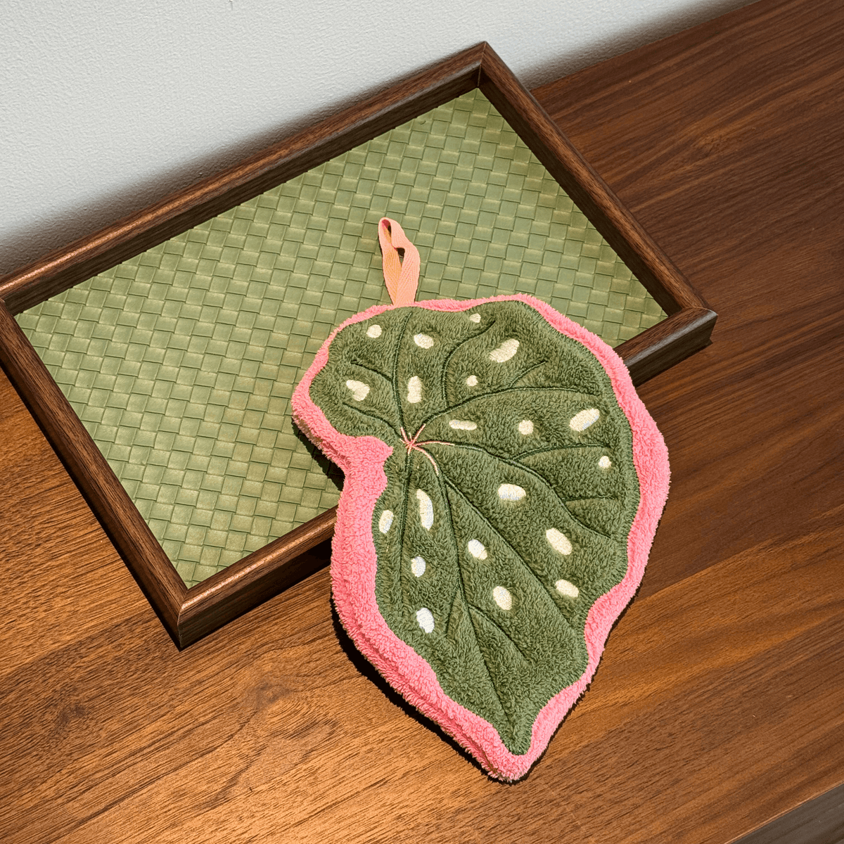 Hanging hand towel with botanical leaf design displayed in a bathroom.
