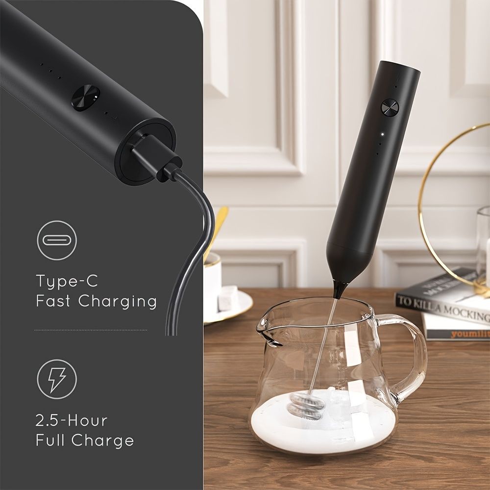 Black rechargeable handheld milk frother with 2 whisk heads frothing milk in a glass pitcher, showing Type-C fast charging