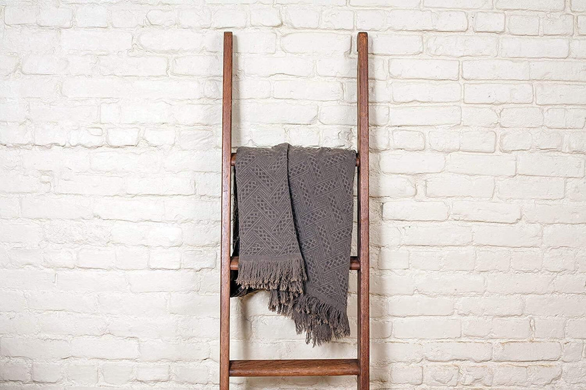 Kasentex cotton knit throw blanket draped over wooden ladder against white brick wall
