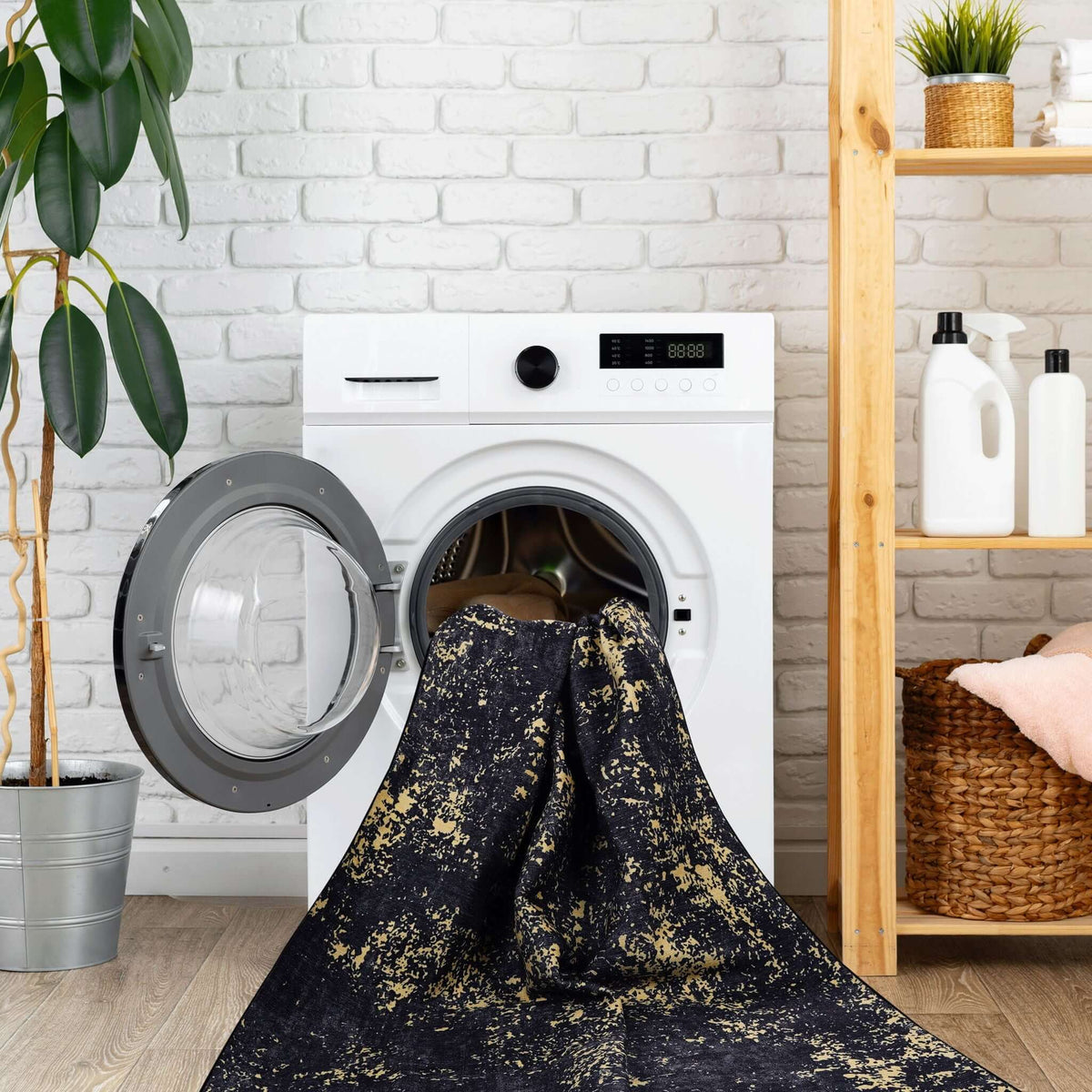 washable stain-resistant area rug in black and gold abstract design being loaded into washing machine