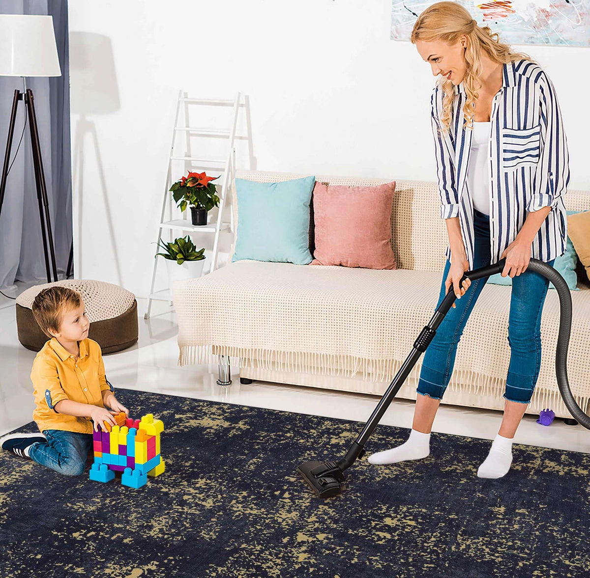 washable stain-resistant area rug in dark color with abstract pattern being vacuumed by woman while child plays