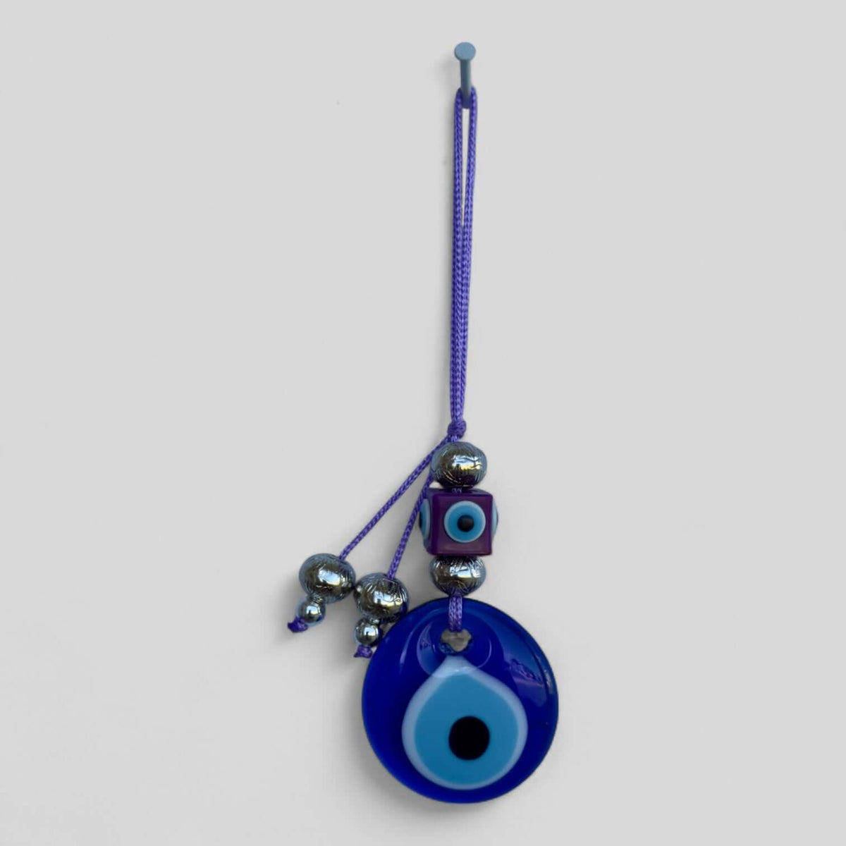 Modern boho evil eye wall hanging displayed above a bed as a headboard accent.