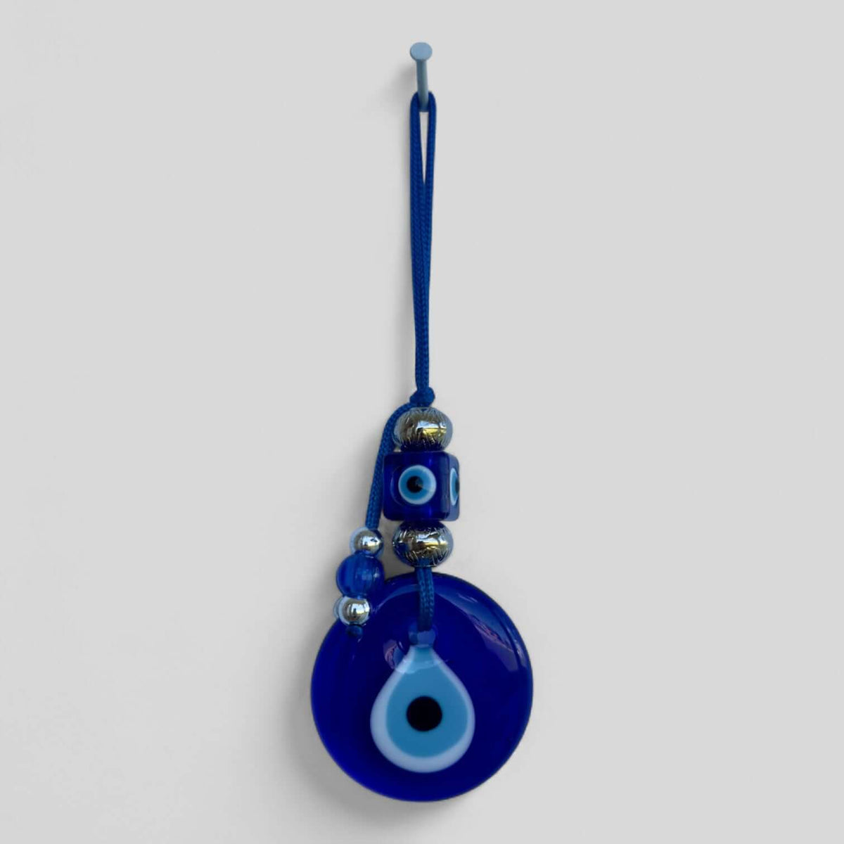 Handcrafted evil eye wall hanging in a modern boho style for entryways and bedrooms.
