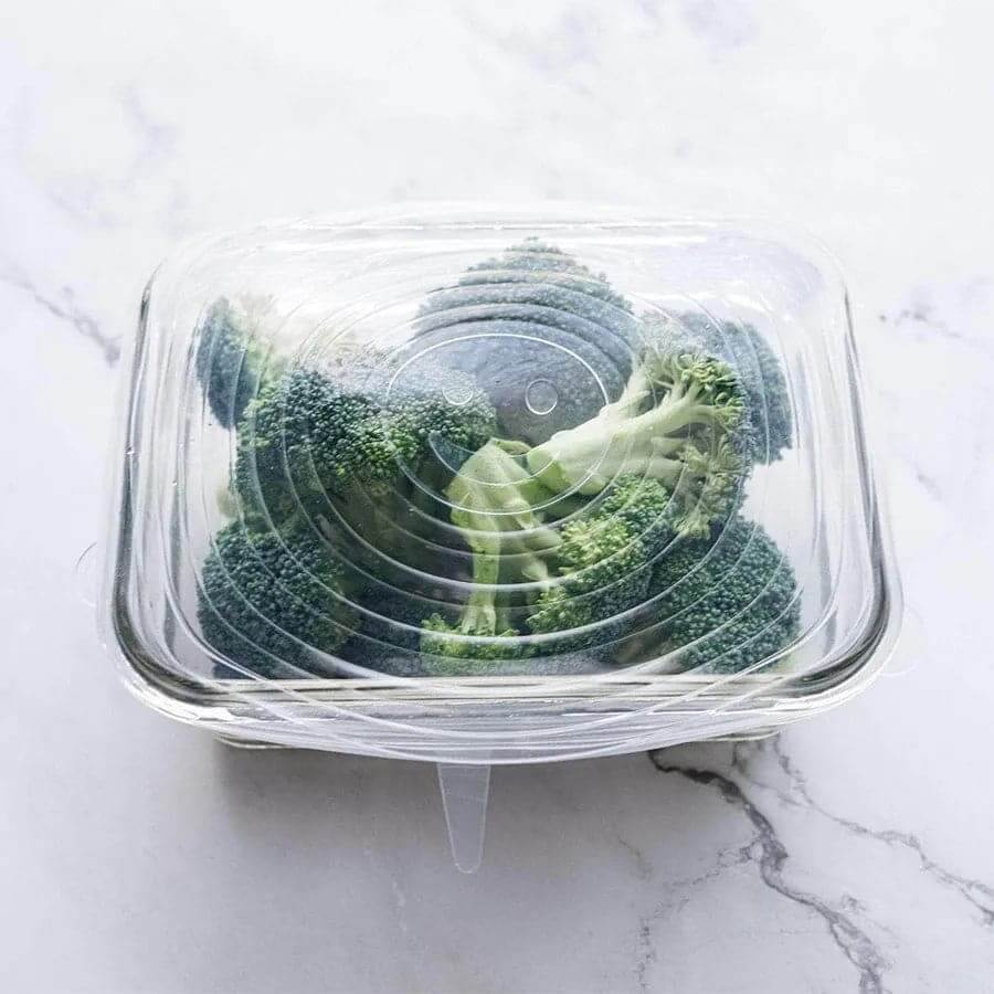 Reusable silicone bowl cover stretched over a bowl of food for airtight storage.