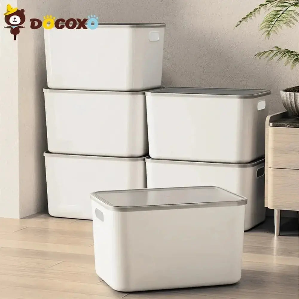 Stackable storage bins with clear lids stacked in a closet holding folded clothes.