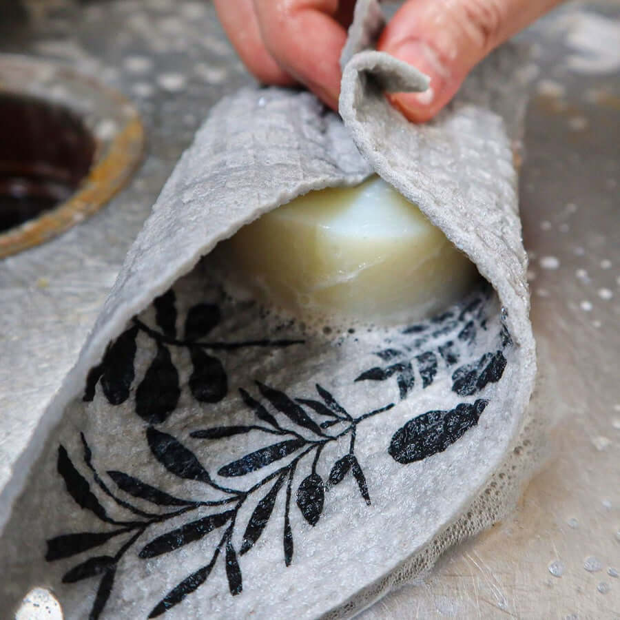 Swedish dishcloth shown wet and absorbent, wringing out excess water.